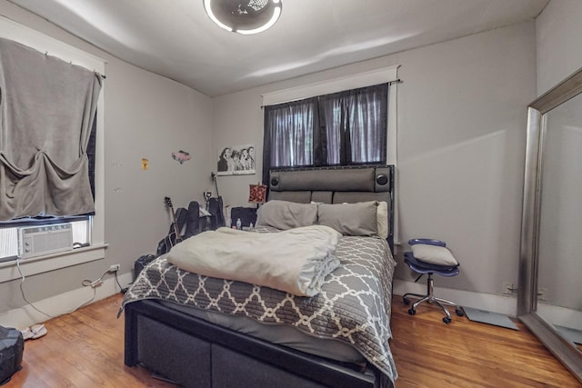 bedroom with cooling unit and wood finished floors