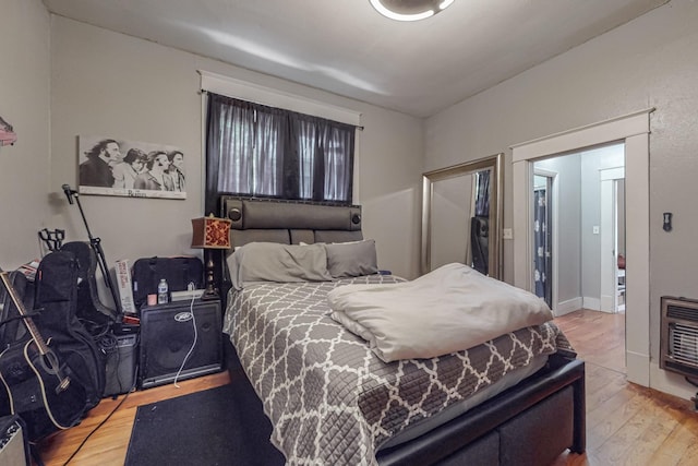 bedroom with wood finished floors and heating unit