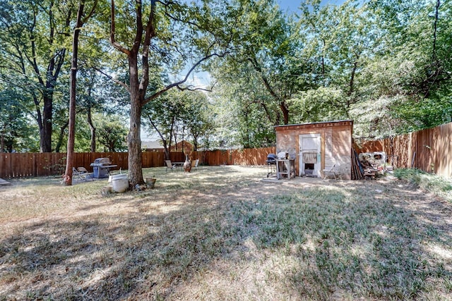 view of yard with a fenced backyard, a storage unit, and an outdoor structure