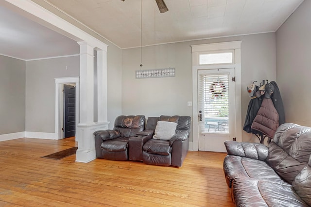 living room featuring ceiling fan, light hardwood / wood-style floors, ornate columns, and ornamental molding