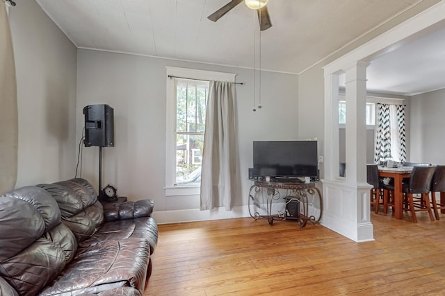 living area with light wood-style floors, decorative columns, and ceiling fan