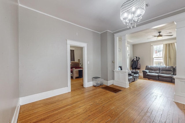 living room featuring light wood-style flooring, ornamental molding, baseboards, and ceiling fan with notable chandelier