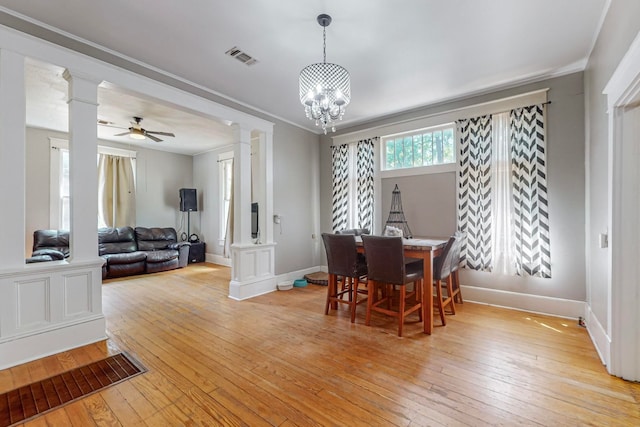 dining area featuring ornate columns, crown molding, ceiling fan with notable chandelier, and light wood-type flooring