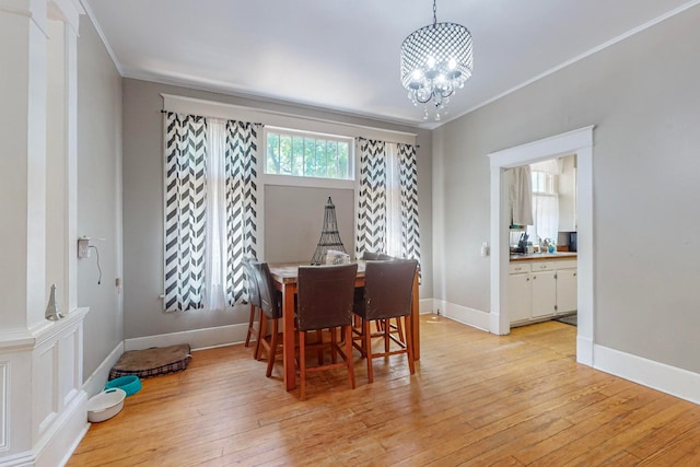 dining room with crown molding, an inviting chandelier, and light wood-type flooring