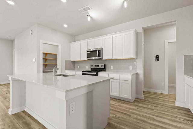 kitchen featuring a kitchen island with sink, sink, stainless steel appliances, and white cabinets