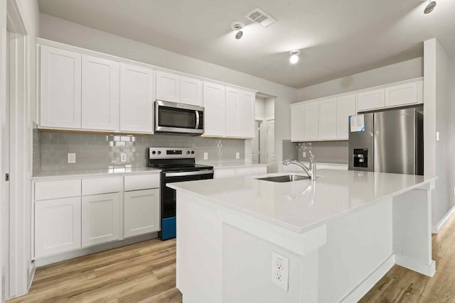 kitchen featuring white cabinetry, sink, stainless steel appliances, and a center island with sink