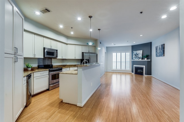 kitchen featuring light hardwood / wood-style flooring, decorative light fixtures, light stone counters, stainless steel appliances, and white cabinets