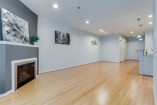 unfurnished living room with light wood-type flooring and sink