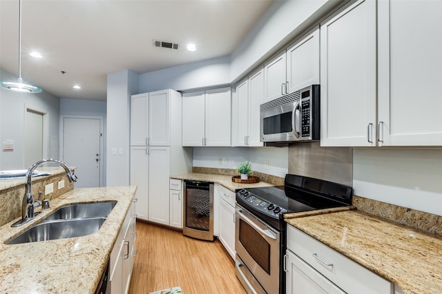 kitchen featuring appliances with stainless steel finishes, pendant lighting, white cabinetry, and sink