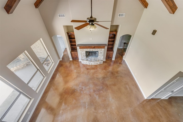 unfurnished living room featuring beamed ceiling, high vaulted ceiling, a fireplace, and ceiling fan