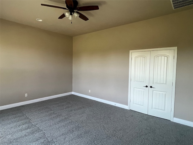 spare room with dark colored carpet and ceiling fan