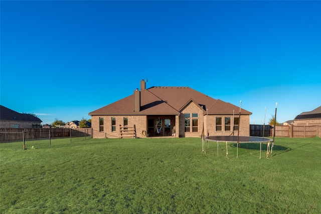 back of property with a lawn and a trampoline