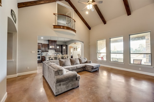 living room featuring ceiling fan, high vaulted ceiling, beamed ceiling, and concrete flooring