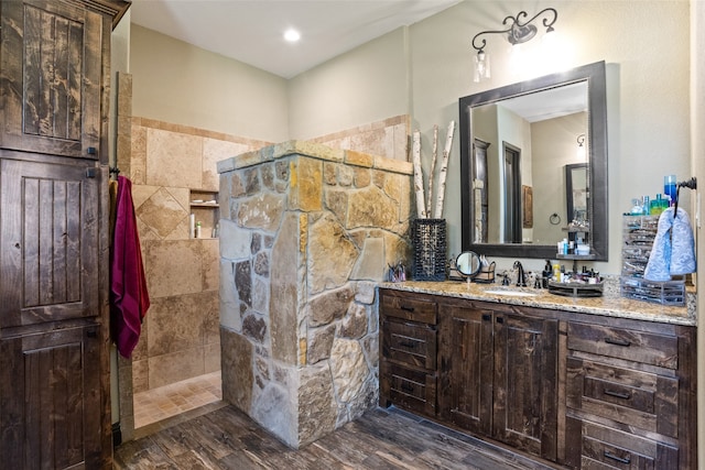 bathroom featuring hardwood / wood-style floors, a tile shower, and vanity