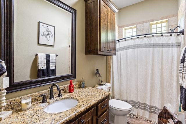 bathroom with toilet, vanity, and curtained shower