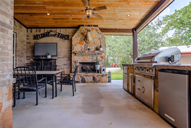 view of patio / terrace with a grill, ceiling fan, an outdoor stone fireplace, and an outdoor kitchen