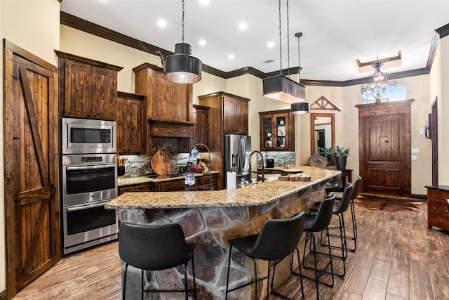 kitchen featuring appliances with stainless steel finishes, hanging light fixtures, light hardwood / wood-style flooring, and a large island