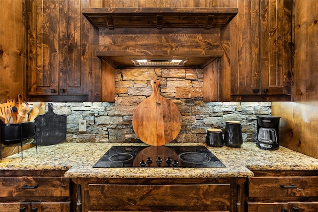 kitchen featuring light stone countertops, black electric stovetop, and wooden walls