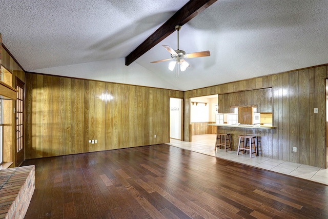 unfurnished living room featuring vaulted ceiling with beams, a textured ceiling, and wood-type flooring