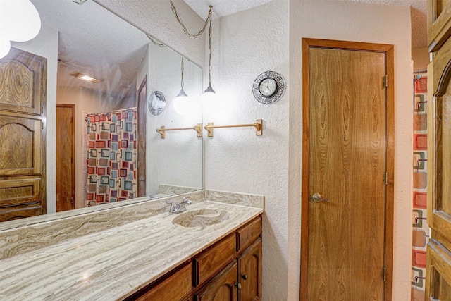 bathroom featuring a textured ceiling, vanity, and curtained shower