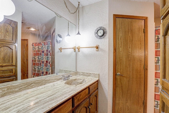 full bathroom featuring a textured wall, a shower with curtain, a textured ceiling, and vanity