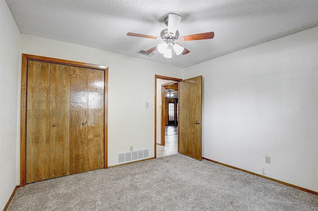 unfurnished bedroom with light colored carpet, a closet, a textured ceiling, and ceiling fan