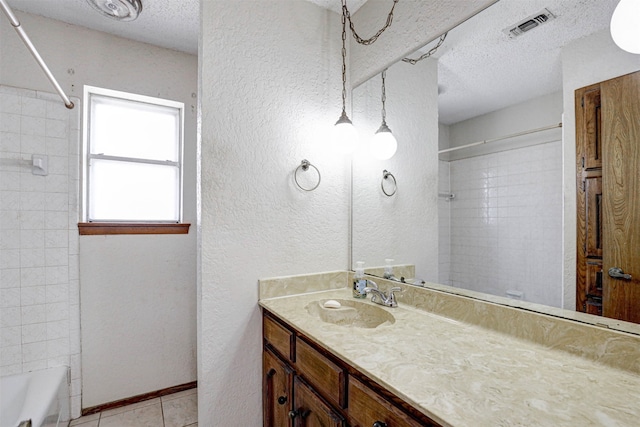 bathroom with tiled shower / bath combo, tile patterned flooring, a textured ceiling, and vanity