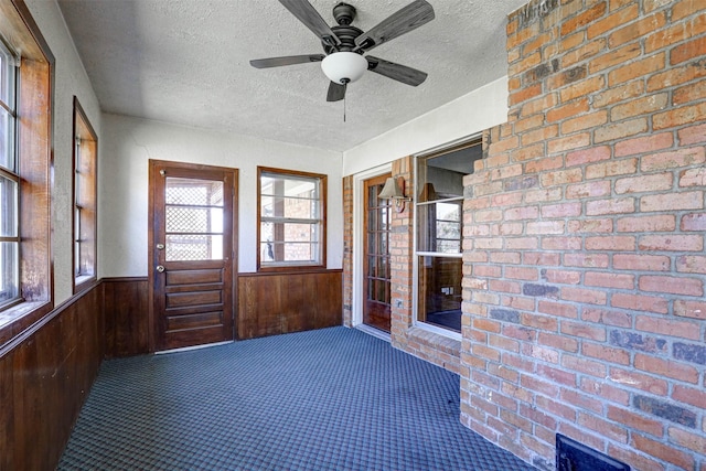 unfurnished sunroom featuring ceiling fan