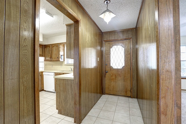 tiled entrance foyer with a textured ceiling, ornamental molding, wood walls, and sink