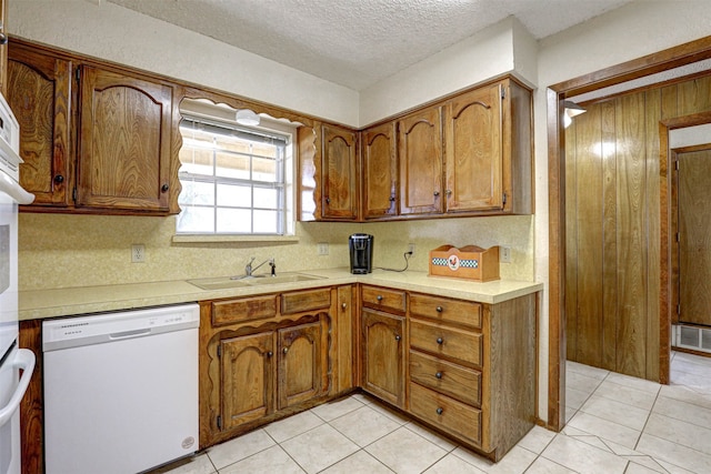 kitchen with sink, light tile patterned flooring, a textured ceiling, and dishwasher