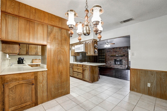 kitchen featuring a fireplace, wood walls, a textured ceiling, and pendant lighting