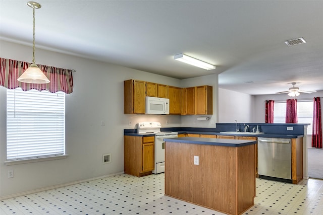 kitchen featuring white appliances, a sink, visible vents, dark countertops, and decorative light fixtures