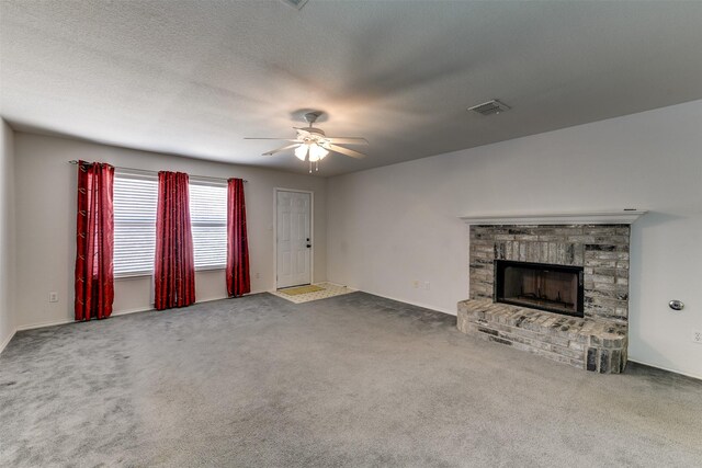 unfurnished living room with a fireplace, carpet flooring, visible vents, and a ceiling fan