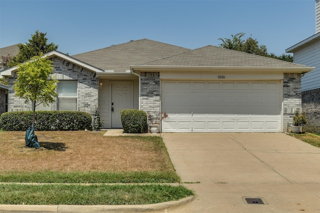 view of front of home with a garage, brick siding, driveway, roof with shingles, and a front yard