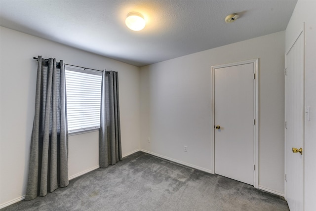 carpeted spare room featuring baseboards