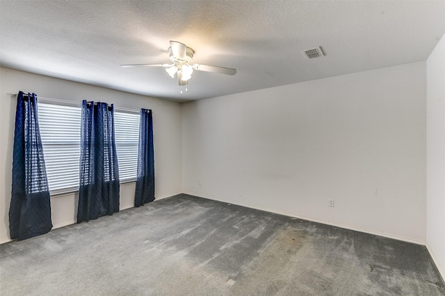 empty room featuring a ceiling fan, visible vents, a textured ceiling, and carpet flooring