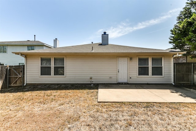 back of house with a yard, a patio area, fence, and a chimney