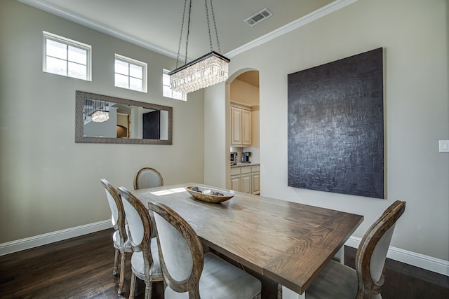 dining room with dark hardwood / wood-style floors, crown molding, and a notable chandelier