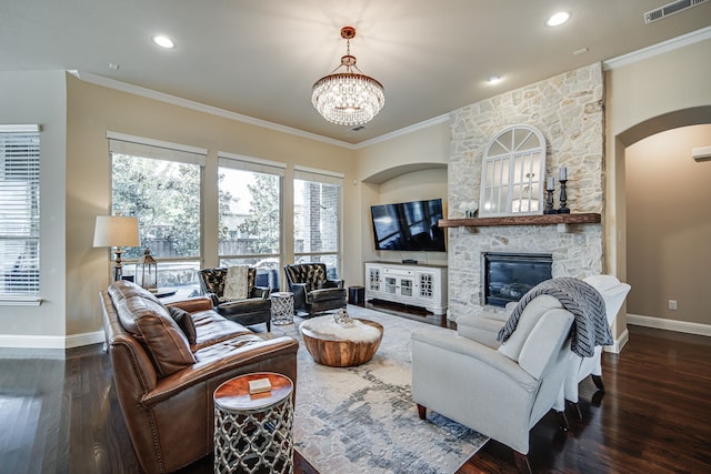 living room featuring a fireplace, ornamental molding, dark wood-type flooring, and an inviting chandelier