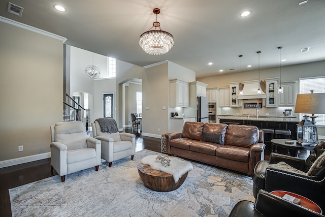 living room with crown molding, sink, wood-type flooring, and a notable chandelier