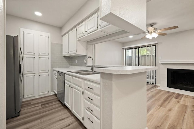 kitchen featuring light countertops, light wood-style flooring, appliances with stainless steel finishes, white cabinets, and a sink