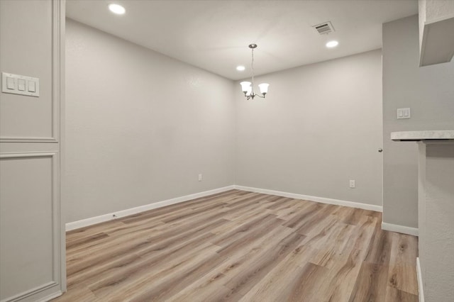 unfurnished dining area featuring an inviting chandelier and light hardwood / wood-style floors