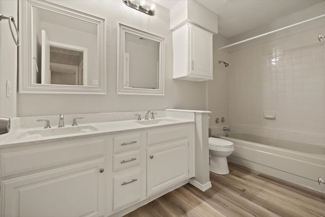 full bathroom featuring tiled shower / bath, vanity, hardwood / wood-style floors, and toilet