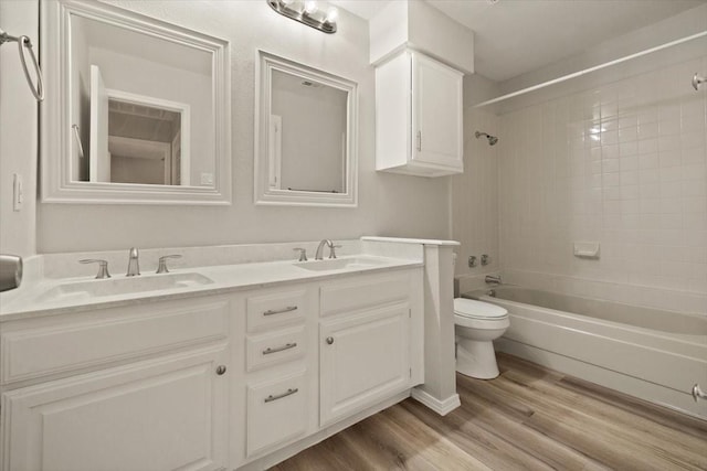 bathroom with a sink, toilet, wood finished floors, and double vanity