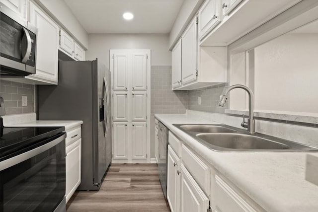 kitchen with appliances with stainless steel finishes, light hardwood / wood-style floors, white cabinets, and backsplash