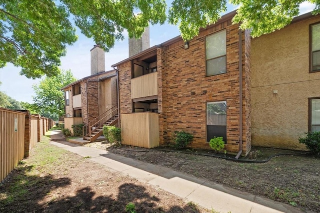 view of building exterior with stairway and fence