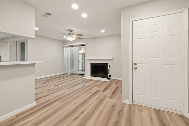 unfurnished living room with visible vents, a fireplace with flush hearth, light wood-style flooring, recessed lighting, and baseboards