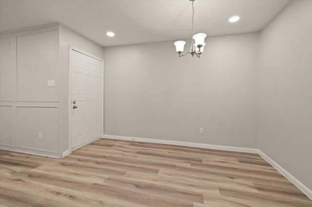 spare room featuring a notable chandelier and light hardwood / wood-style flooring