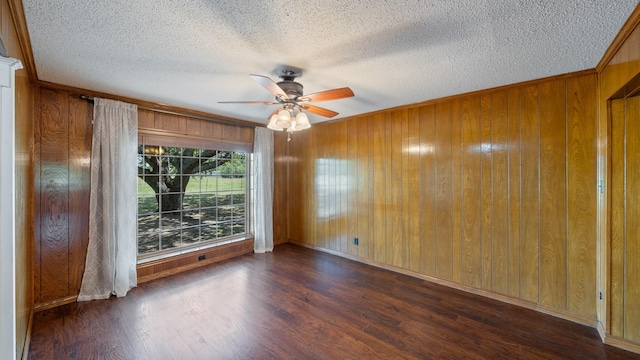 unfurnished room with a ceiling fan, wood walls, a textured ceiling, and wood finished floors