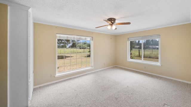 carpeted spare room with ceiling fan, crown molding, baseboards, and a textured ceiling